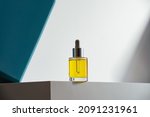 face oil in glass bottle with dropper on white podium and geometric teal background. Modern self-care minimalism in cosmetics and skin-care. Hero shot