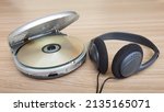 Small photo of Open cd player with disk and earphone on wooden background.