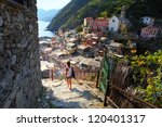 Young woman walking on stairs of small street of Vernazza town. Italy