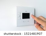 Man hand setting the room temperature on a modern programmable thermostat water heater (boiler). Smart home.