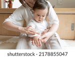A women wipes baby's arm with wet tissue 