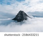 Aerial photograph. Detail of the peak of Beriáin, in the Andía mountain range, rising among the white clouds. In the background a deep blue sky with lots of clouds.