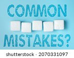 Small photo of Inspiration showing sign Common Mistakes Question. Conceptual photo repeat act or judgement misguided making something wrong Stack of Sample Cube Rectangular Boxes On Surface Polished With Multi