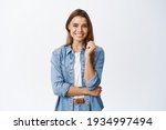 Happy successful woman standing in casual outfit, smiling pleased at camera and looking confident, standing against white background