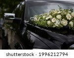 A black wedding car decorated with white roses, bridal bouquet, just married