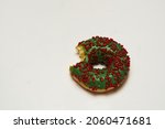 Donut close-up on white background. Donut bitten off isolated. Green donat wit red decorative candy