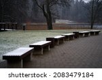 Winter cityscape. semicircular row of wooden benches covered with snow. snowy road in the park, copy space