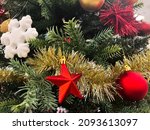 Christmas background, green pine branches festive background. New year decoration with red star and bubble, white snowflake. Botanical selective focus.