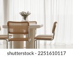 Interior of light dining room with white table, rattan chairs. Japandi interior concept