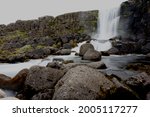Long exposure of Öxarárfoss waterfall in Thingvellir National Park, Iceland, set against an overcast sky