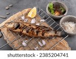 Small photo of Grilled sea bass with lemon on the grid. Grilled spicy fish sea bass . Baked sea Bass fish. Top view