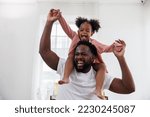 Small photo of enjoy happy love black family african american father carrying daughter little african girl child smiling in the white living room at home. Happy black African American father day concept.