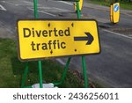 Small photo of Diverted traffic road sign with arrow. informative sign for motorists at works site showing reroute