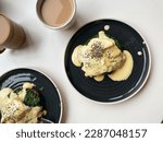 Small photo of Two plates of eggs florentine and coffee eith milk
