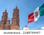 Small photo of Mexican flag waving with Parroquia Cathedral Dolores Hidalgo Mexico behind, Cradle of National Independence Where Father Miguel Hidalgo made his Grito starting the 1810 War of Independence in Mexico