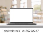 Laptop with blank screen on marble table with cafe coffee shop blur background