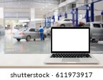 laptop computer on wooden table with blurred car service centre background