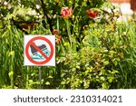 Small photo of city flower bed with a sign forbidding trampling on flowers. trample plants. flower bed in the city. lawn prohibition sign. High quality photo
