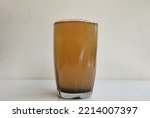 Glass filled with brown color bad, unhygienic, contaminated, undrinkable, impure, muddy and dirty drinking water isolated on white table background with copy space. Closeup side view. Impurity concept