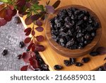 Small photo of Berries of black barberry in wooden bowl and spoon. Spice barberry blue. Dry berries of barberries.