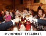 Small photo of Happy people clang their glasses over round dinner table with roses