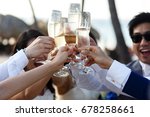 Small photo of Newlyweds and friends clang their glasses standing outside