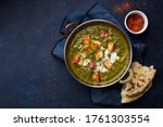 Flat lay top view of vegetarian palak paneer starter. Indian cuisine, curry dish with soft cheese and spinach on concrete background with copy space