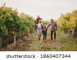 Happy family taking a walk at vineyard. Sunny autumn day.