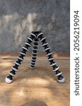 Small photo of A camera gorillapod standing on a wooden board on a dark gray background.