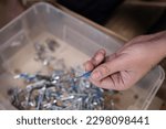 Man holding a screw for carpentry, furniture repair, repair and assembly of the house. Step 1: Pour all the screws or bolts into the box, close up, details when assembling furniture, storage box