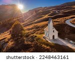 South Tyrol, Italy - The Chapel of San Maurizio (Cappella Di San Maurizio) at the Passo Gardena Pass in the Italian Dolomites at autumn with warm colorful sunset and blue sky