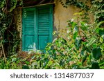 Small photo of Old unideal greenish closed window on wooden peeling wall of aged rustic building. Retro background of vintage wood house