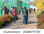 Small photo of Grandma and mom with a baby carriage walk near the football stadium with the townspeople on an autumn day