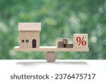 Small photo of Interest rate up and Banking concept, Model house with Percentage symbol icon on wood scale seesaw on natural green background, Fixed Rate