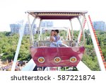 Enamored couple of beautiful people, boy and girl kissing, hugging, posing for photo, ride on ferris wheel, smiling, laughing and sit in booth ferris wheel on background of city, sky and trees at an