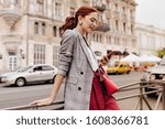Red haired woman in stylish outfit chatting on phone