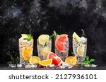 Small photo of Gin tonic and citrus cocktails set. Alcoholic drinks with lime, lemon, grapefruit, orange, soda and herbs in highball glasses, black bar counter background. Summer cocktail party