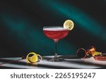 Small photo of Pink lady alcoholic cocktail drink with gin, grenadine syrup, lemon juice and egg white, dark green background, bright hard light and shadow pattern
