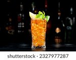 Small photo of Boston tea alcoholic cocktail drink with white rum, dry gin, vodka, tequila, liquor, lemon juice, cola and ice in highball glass, dark background, bar tools and bottles