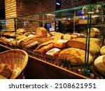 Delicious loaves of bread in a bakery on a showcase. Various types of buns loaves, baguettes. Rye, buckwheat, bran, gluten-free, wheat bread on bakery shelves. Confectionery, private bakery in store