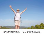 Active senior man standing and enjoying the top of the world opening arms - concept of no limit age and travel for old people