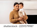 Stock photo of smiley woman holding her little baby and looking at camera.