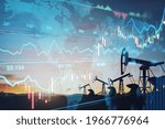 Rise in gasoline prices concept with double exposure of digital screen with financial chart graphs and oil pumps on a field