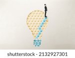 European businessman in suit standing on abstract pattern light bulb on light background with mock up place. Idea, growth and success concept