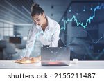 Small photo of Financial analyzing and market forecast concept with young woman working with data, making notes in notebook and growing digital forex chart diagram and candlestick, double exposure