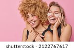 Small photo of Two positive women have friendly relationships embrace and smile broadly apply beauty patches under eyes enjoy softness of skin pose against pink background. Rejuvenation and wellness concept