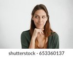 Small photo of Headshot of cunning beautiful woman with straight dyed hair looking aside holding hand under chin indenting to realize tricky plan. Attractive female having sly expression while looking aside