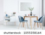 Small dining table with two upholstered chairs and a white cabinet in a bright, open space living room interior