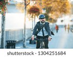 Hipster businessman commuter with electric bicycle traveling home from work in city.