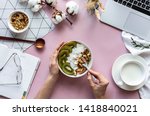 Female hand hold spoon over healthy breakfast concept bowl enjoy detox morning meal on work table background with laptop milk, woman eat natural granola nutrition detox food in home office, top view